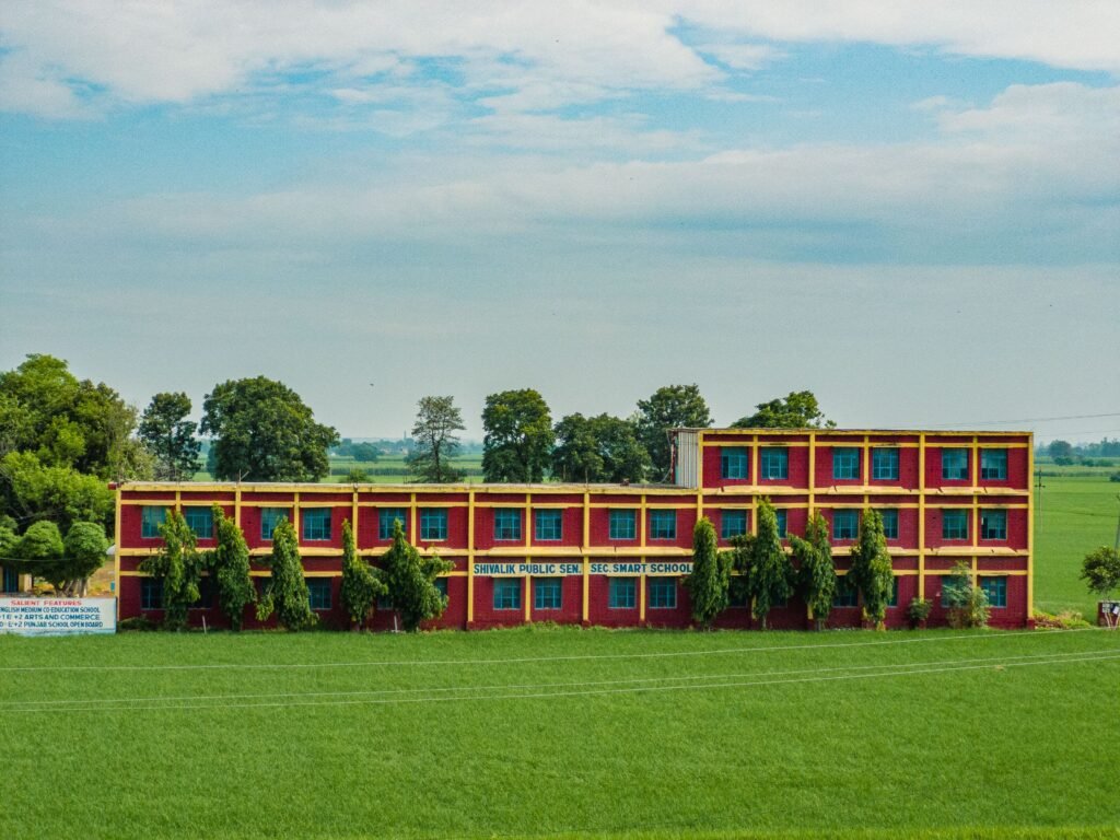 Web Design Colorful school building amidst lush green fields in Ludhiana, Punjab, India.